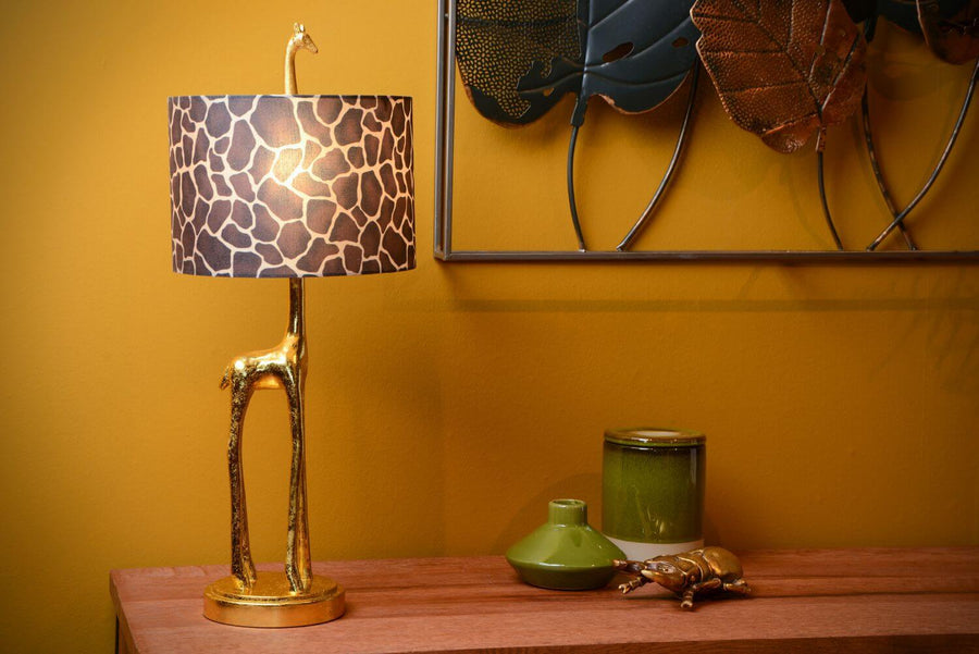 Vue de profil de la lampe girafe dorée, abat-jour allumé, décor mural et vase vert