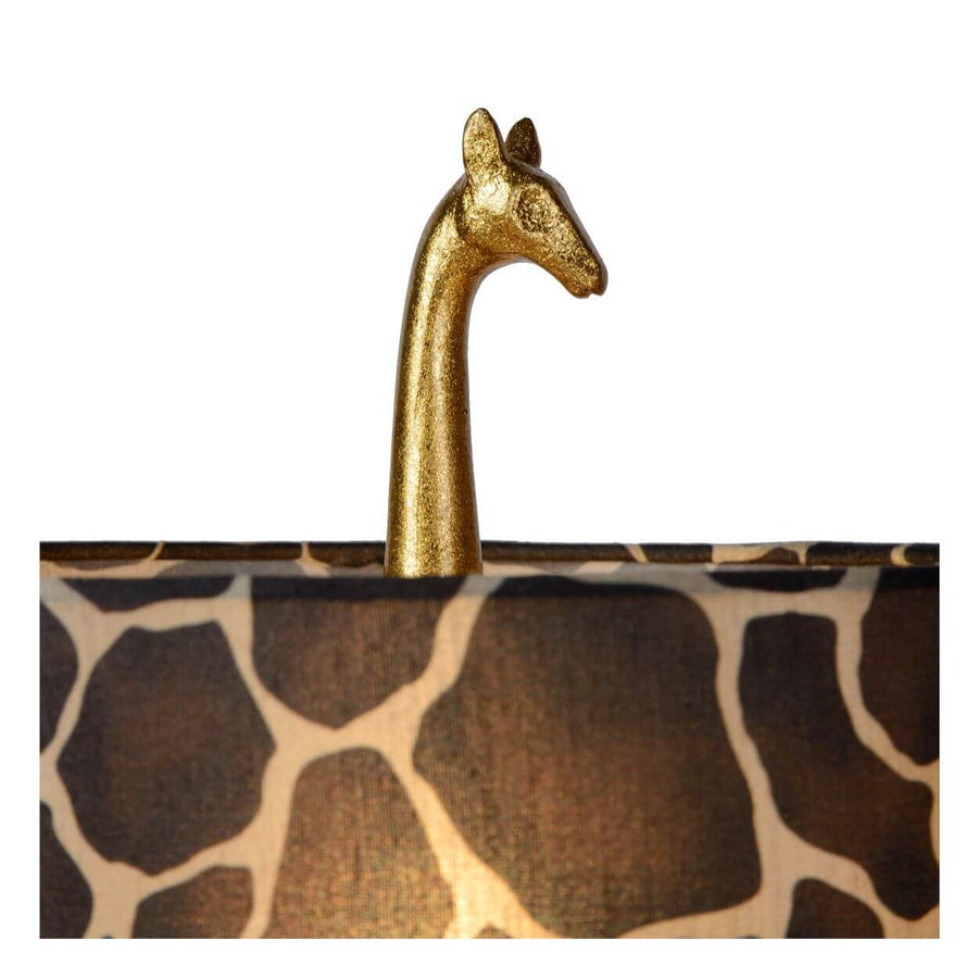 Détail de la tête de girafe dorée mat dépassant de l'abat-jour à motif