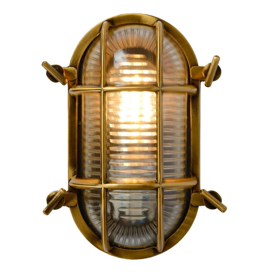 Vue de face sur fond blanc, applique dorée allumée, verre strié et grille apparente.