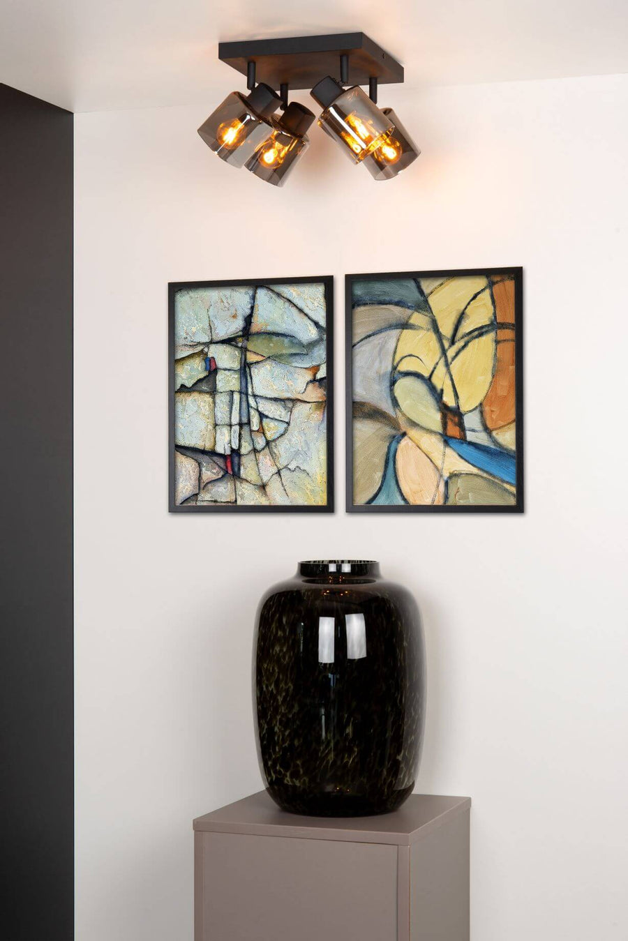 Plafonnier quatre lumières en verre fumé allumé, fixé au plafond blanc.