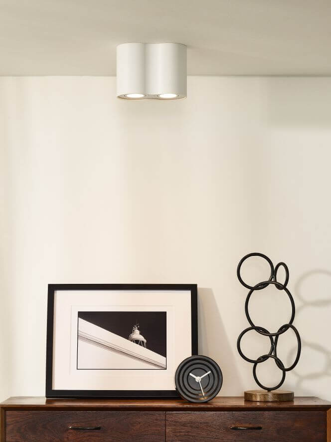 Vue rapprochée du luminaire blanc à deux diffuseurs, intégré dans un intérieur épuré et lumineux.