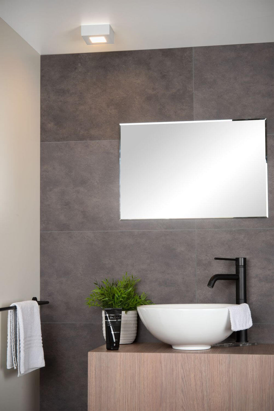 Mise en situation du luminaire carré blanc fixé au plafond dans une salle de bain moderne.