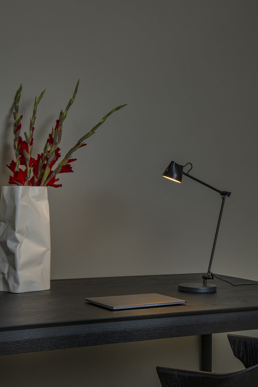 Vue rapprochée de la lampe de bureau noire allumée près d'un vase froissé