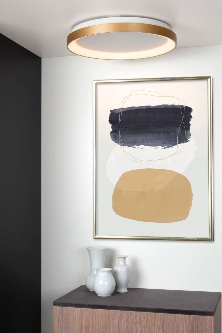 Vue de trois quarts du plafonnier allumé au-dessus d'un tableau abstrait bleu et ocre