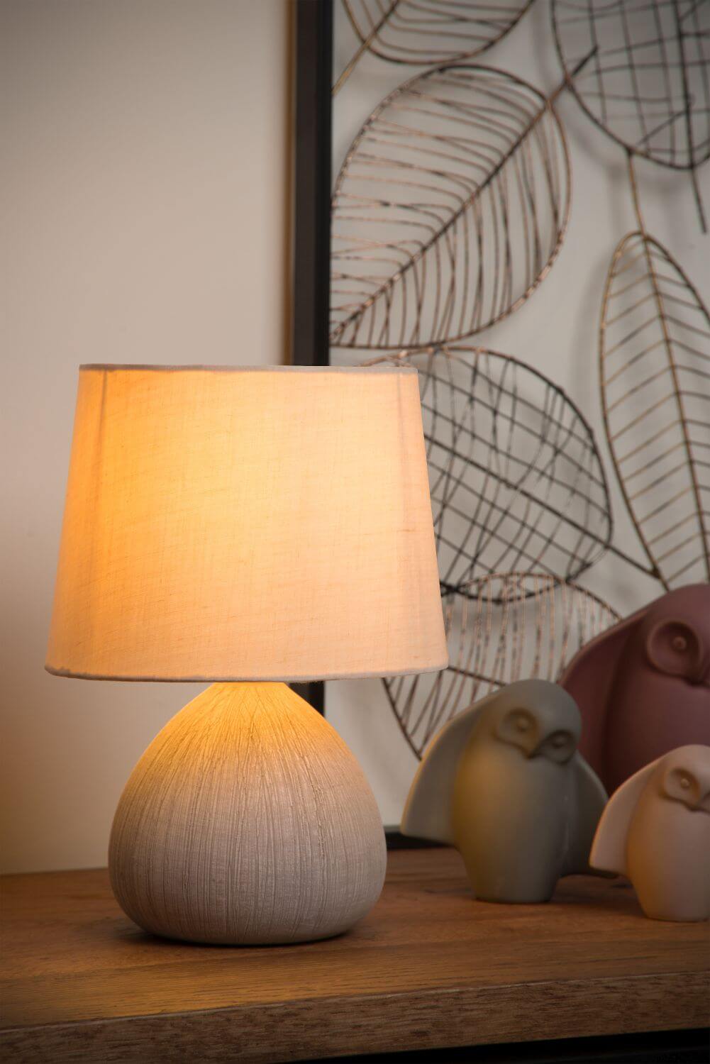Mise en ambiance chaleureuse : lampe allumée près de chouettes décoratives et cadre feuillage.