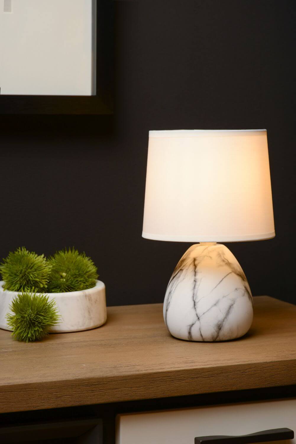 Mise en ambiance : lampe allumée près d une coupe de plantes décoratives