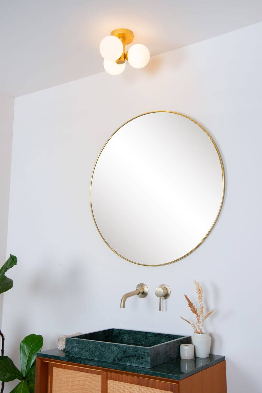 Plafonnier doré installé au plafond au-dessus d'une vasque en pierre verte.