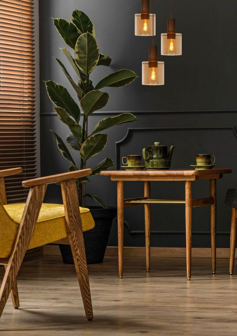 Vue rapprochée de la suspension allumée dans un intérieur sombre, avec plante verte.