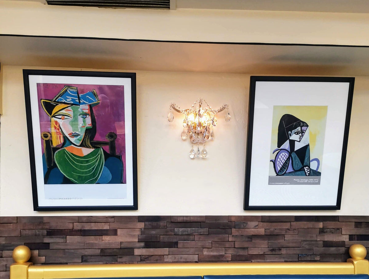 Applique allumée fixée au mur entre deux tableaux, ambiance chaleureuse