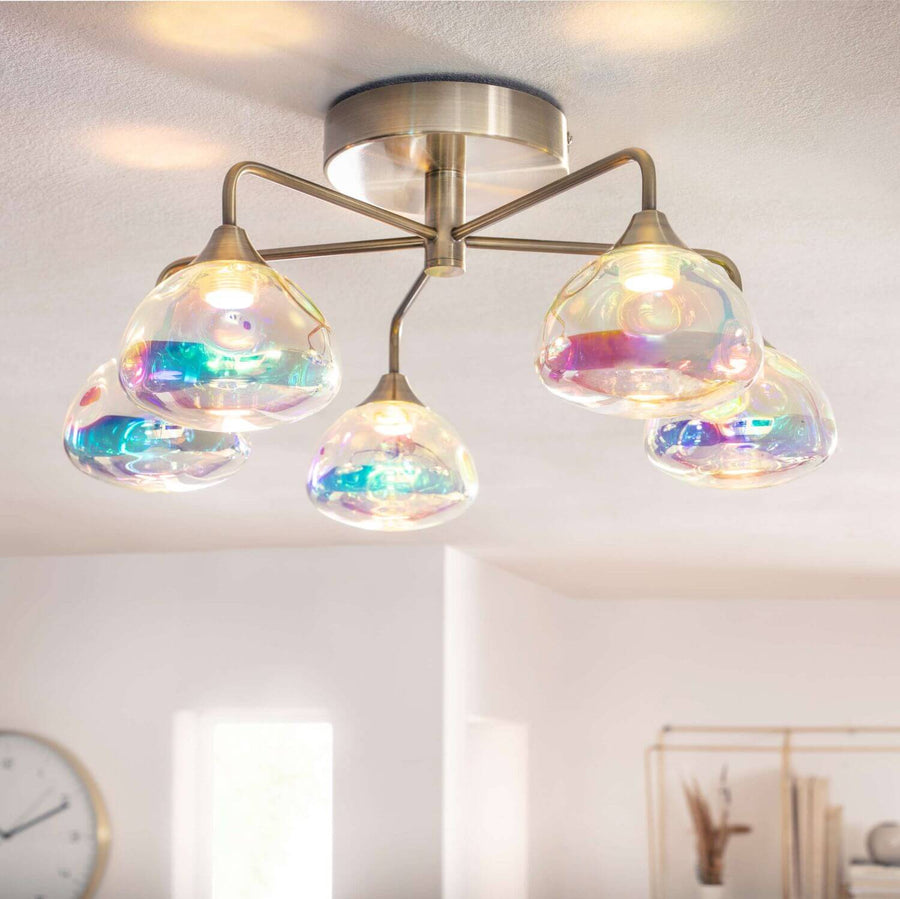 Plafonnier allumé au plafond dans un séjour clair, reflets arc-en-ciel sur le verre