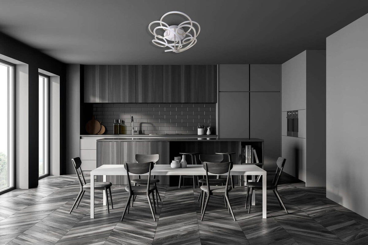 Mise en ambiance dans une cuisine sombre, plafonnier allumé au-dessus de la table.