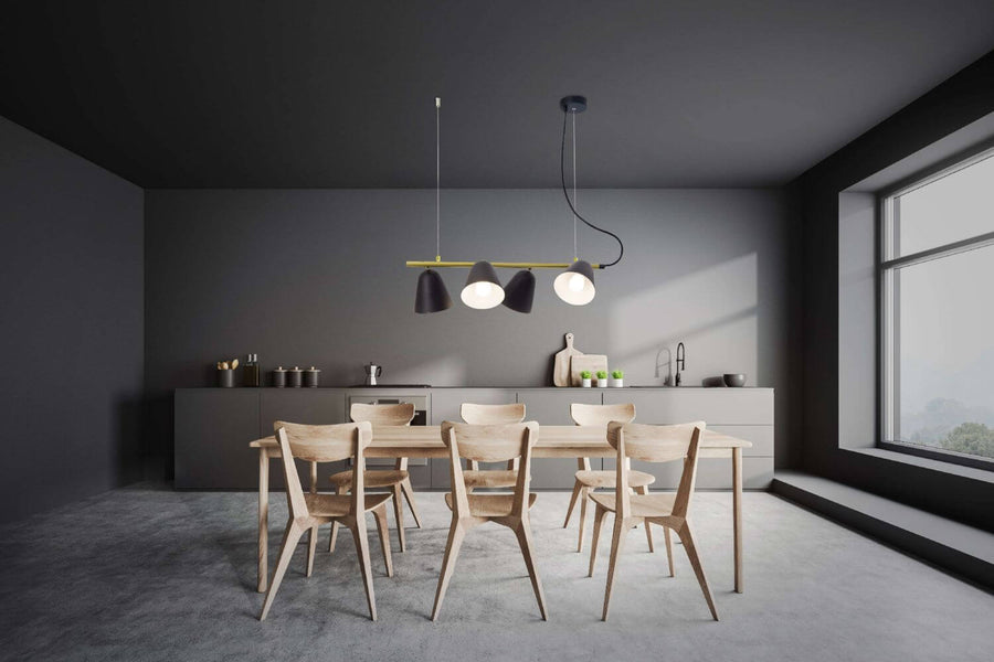 Salle à manger sombre : suspension à quatre abat-jour éclairant une table en bois et des chaises.
