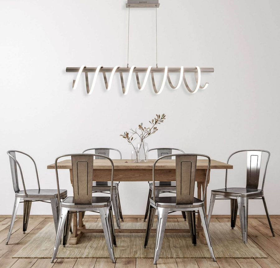 Luminaire installé au-dessus d'une table en bois entourée de chaises métal.