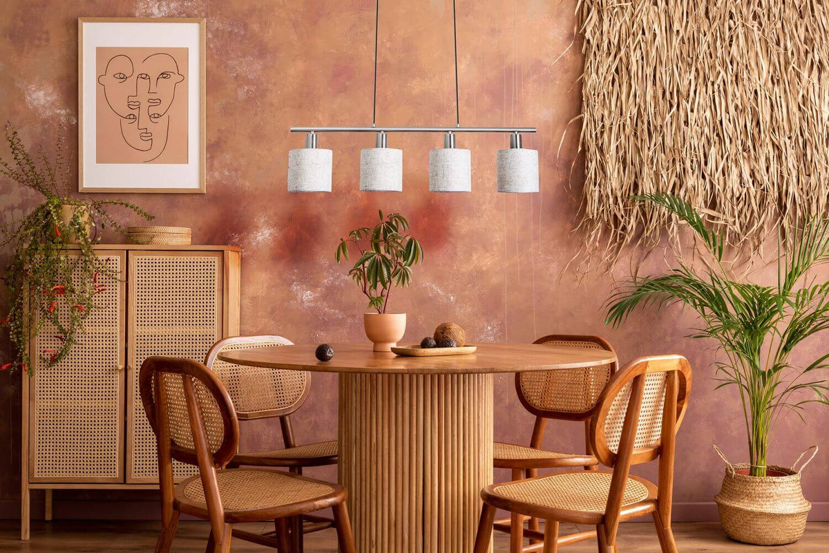 Ambiance bohème chaleureuse : suspension au-dessus d'une table ronde, mur ocre et meubles en rotin.