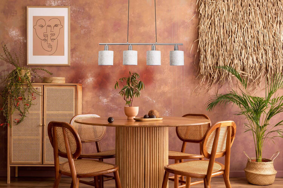 Ambiance bohème chaleureuse : suspension au-dessus d'une table ronde, mur ocre et meubles en rotin.