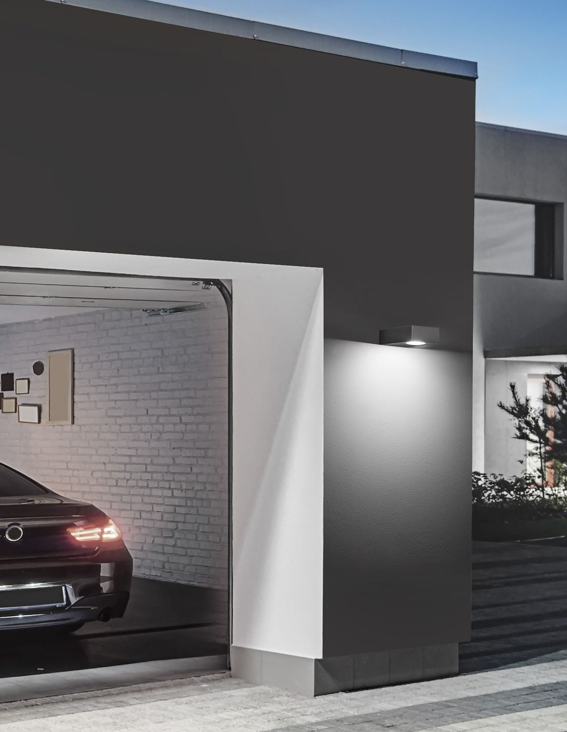 Mise en ambiance de nuit sur une façade, applique murale allumée près du garage
