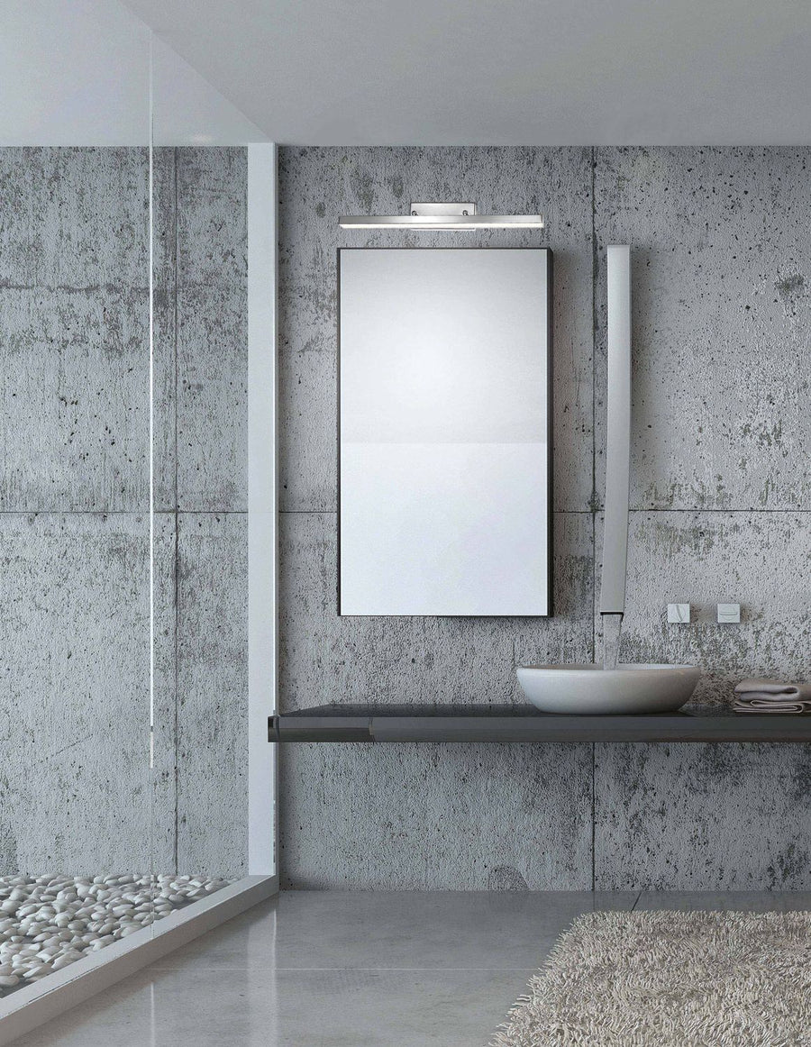 Applique murale chromée fixée au-dessus d'un miroir dans une salle de bain béton