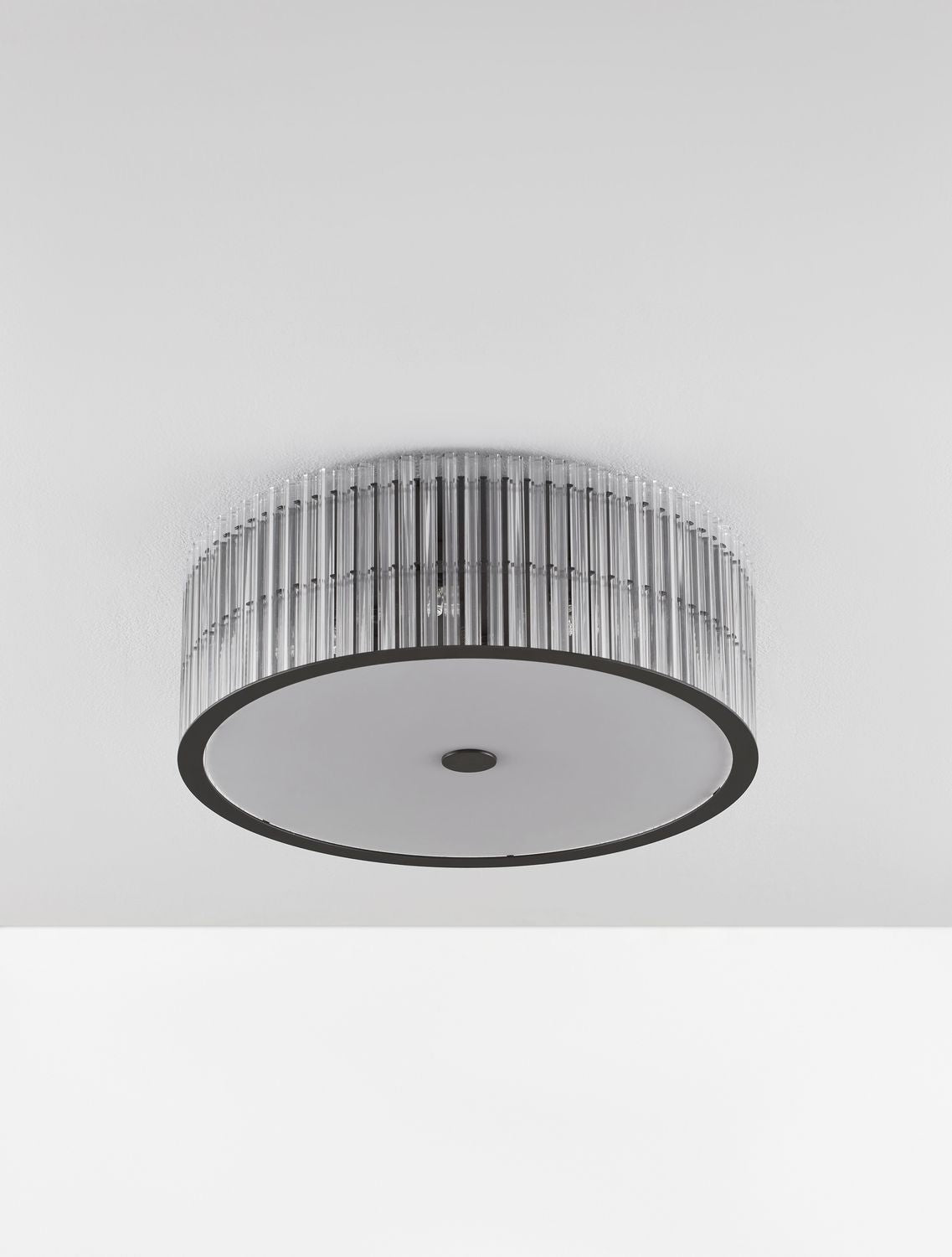 Vue de dessous du luminaire fixé au plafond, diffuseur blanc et cerclage noir.