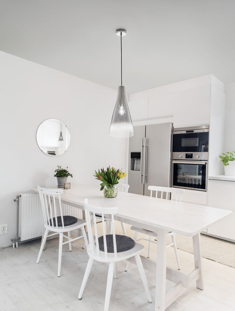 Suspension conique en verre fumé suspendue au-dessus d'une table de cuisine blanche