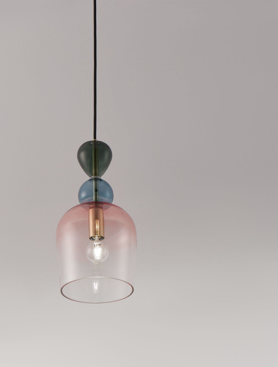 Détail du globe en verre rose et de l'ampoule allumée à l'intérieur.