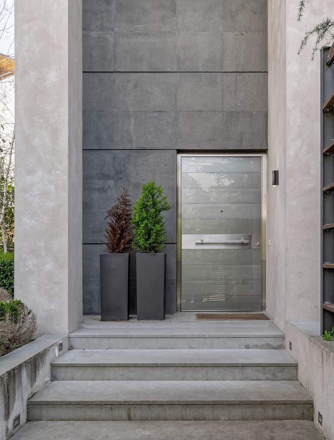 Entrée moderne en béton gris avec applique murale noire près de la porte
