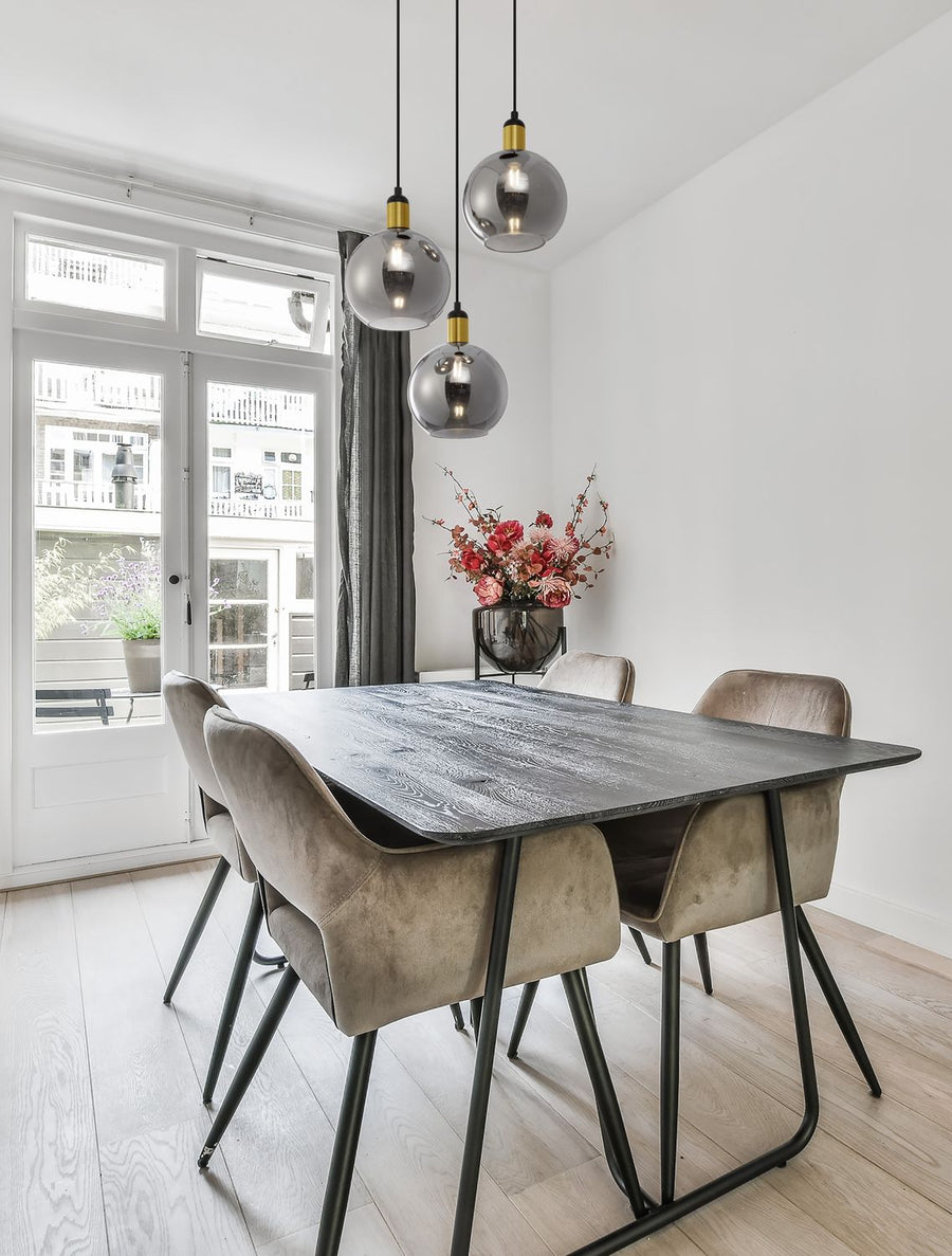 Suspension à trois globes fumés installée au-dessus d'une table de salle à manger lumineuse