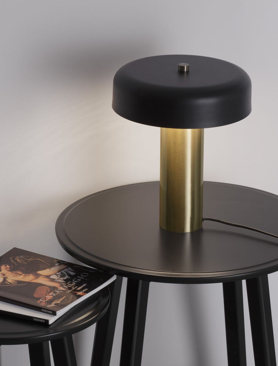 Lampe à poser noire et laiton doré sur une table d'appoint