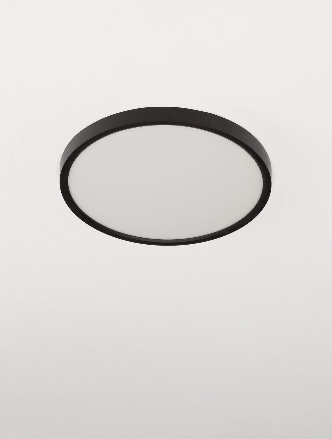 Plafonnier circulaire noir vu de biais, large diffuseur blanc opale au centre.