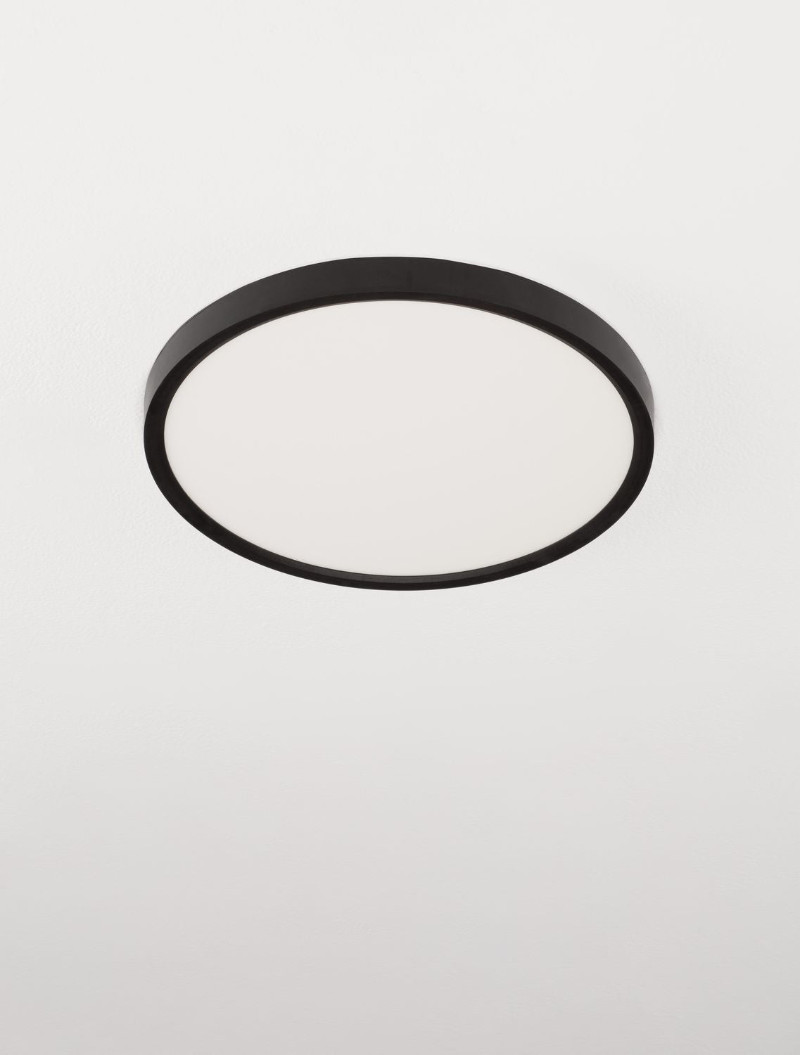 Vue presque frontale du luminaire rond, cerclage noir fin et vasque blanche.