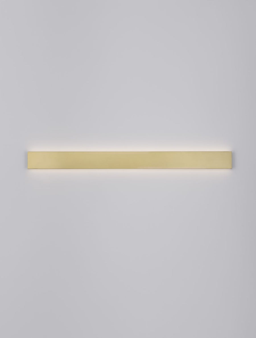 Bandeau doré allumé projetant une lumière rasante sur le mur blanc