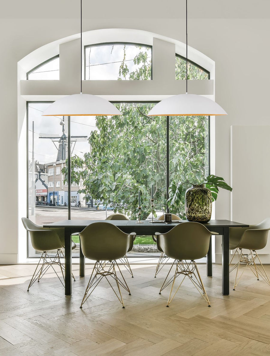 Deux suspensions blanches suspendues au-dessus d'une table de salle à manger devant une grande fenêtre.