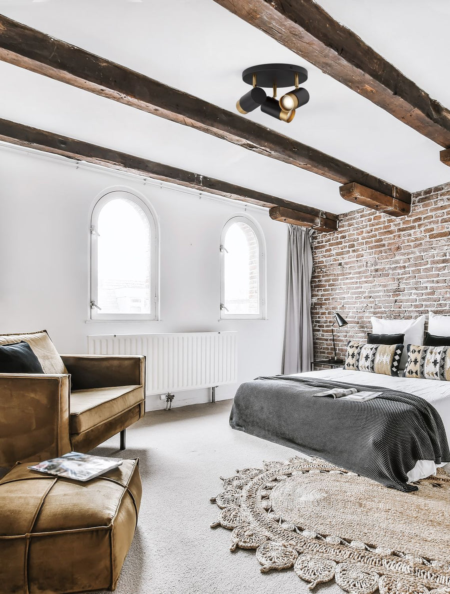 Plafonnier noir et laiton fixé au plafond à poutres d'une chambre style industriel
