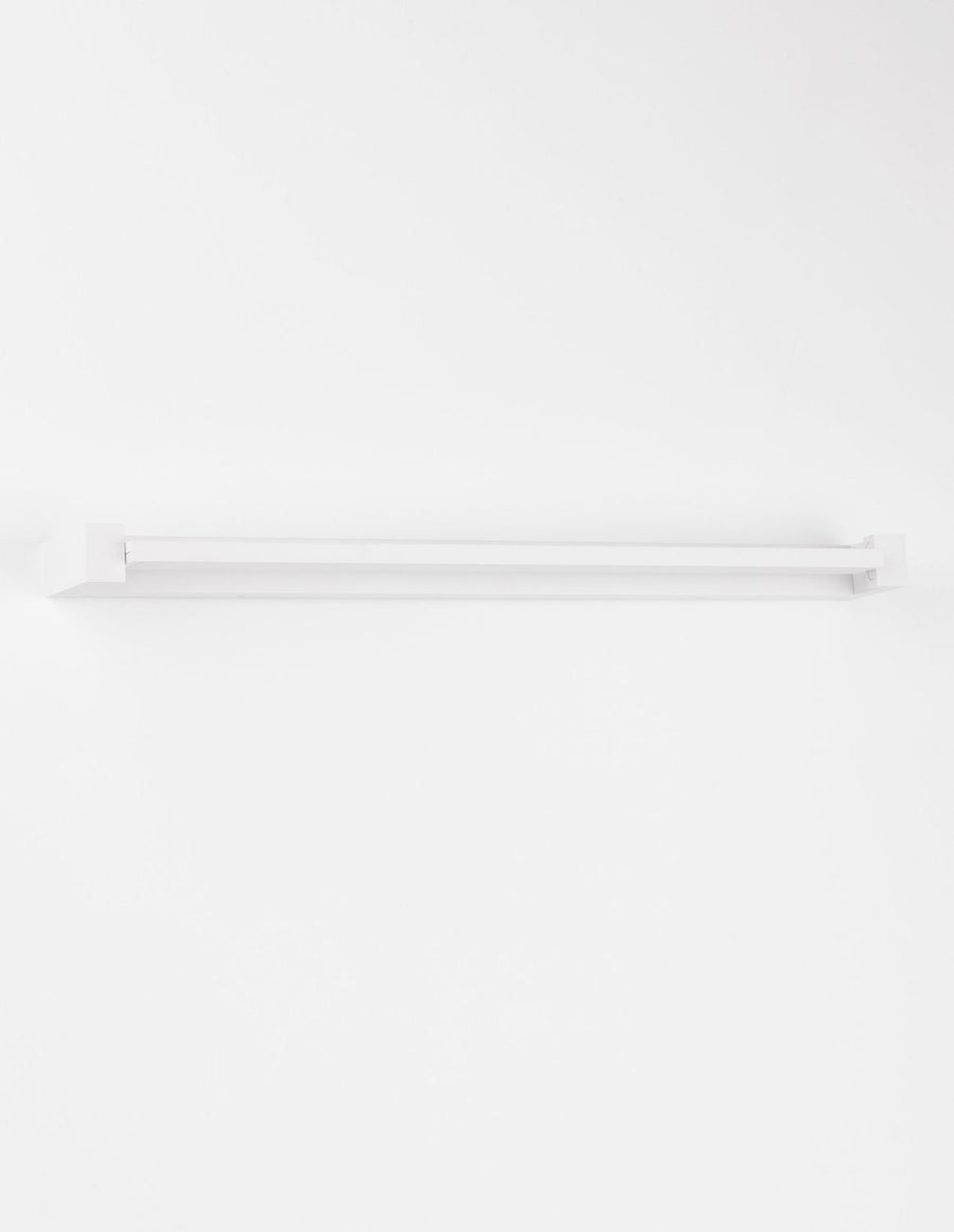 Vue de face éteinte, longue réglette fine fixée sur le mur blanc