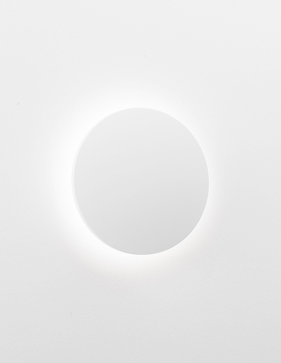 Halo lumineux diffus autour de l'applique ronde blanche, ambiance murale épurée