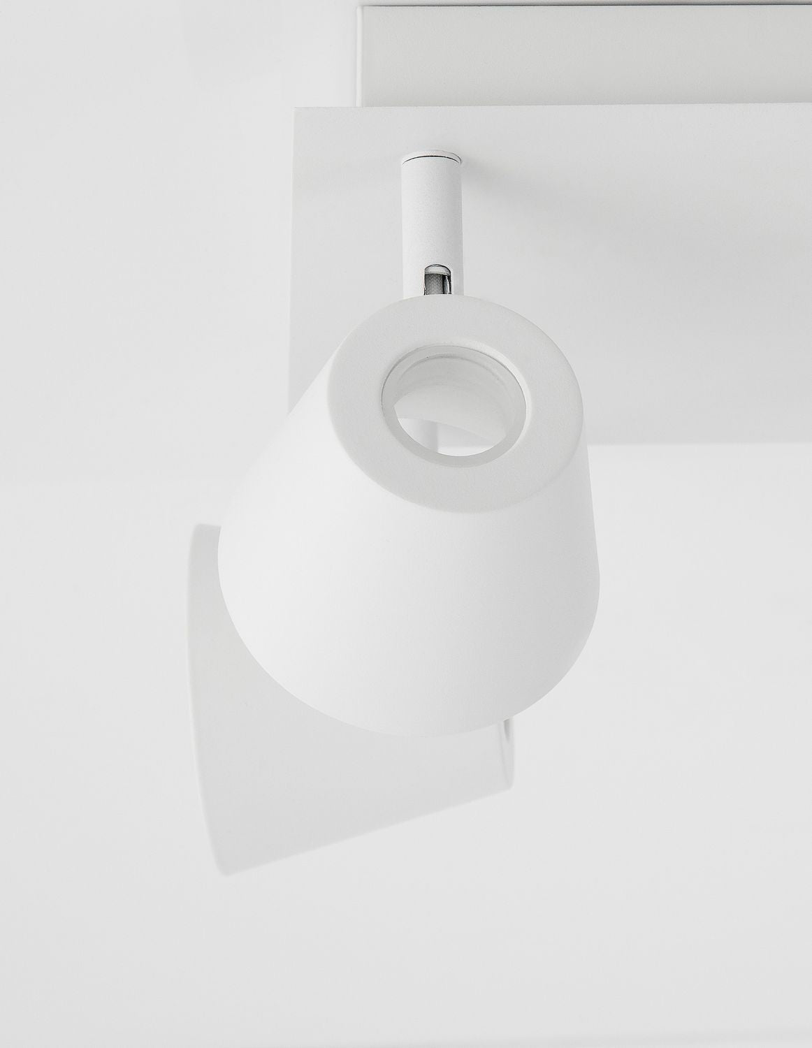 Détail d'un projecteur cylindrique blanc et de son articulation sur la platine.