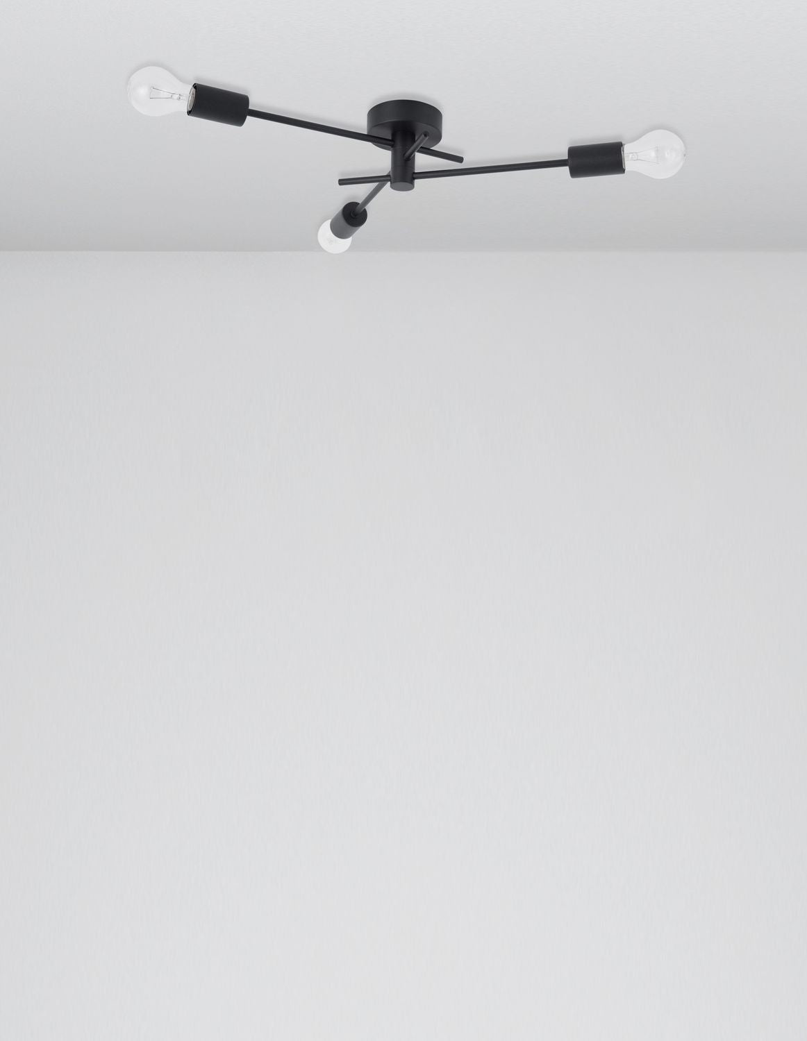 Vue en situation du luminaire noir fixé au plafond, bras orientables et ampoules apparentes.