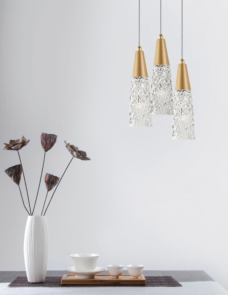 Suspension trois lumières dorées au-dessus d'une table avec vase et service à thé