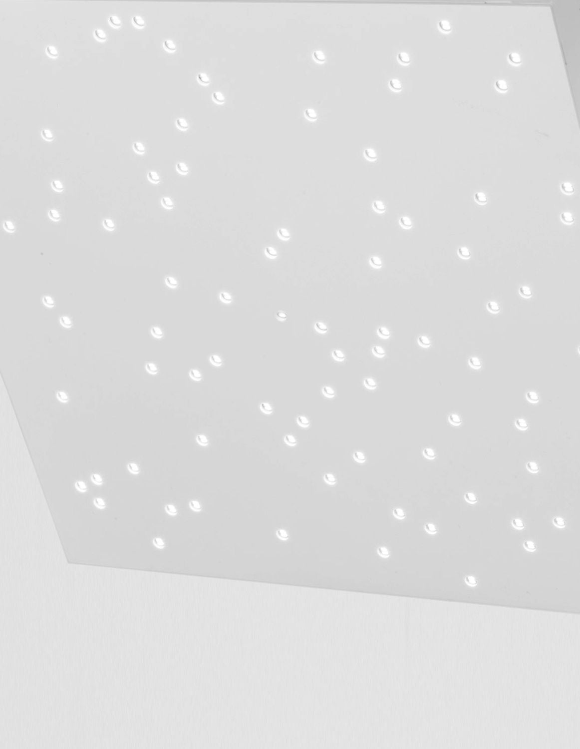 Détail rapproché des perforations allumées, points de lumière blanche répartis sur la surface