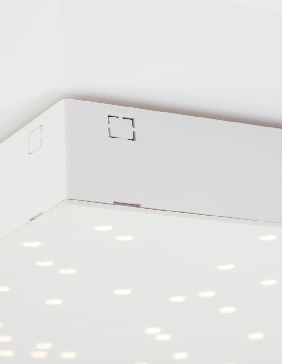 Détail du chant et des fixations du panneau blanc posé contre un plafond