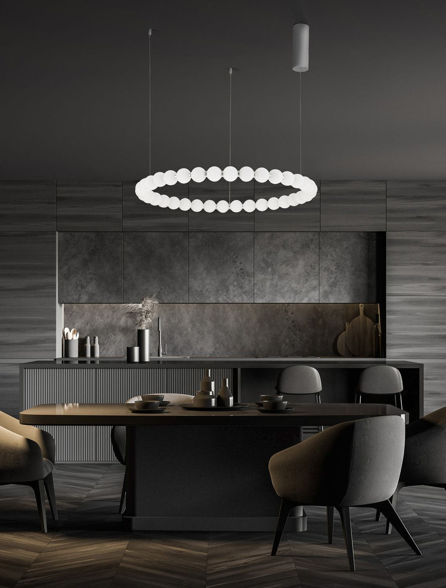 Suspension anneau en perles de verre blanc éclairant une salle à manger sombre et moderne