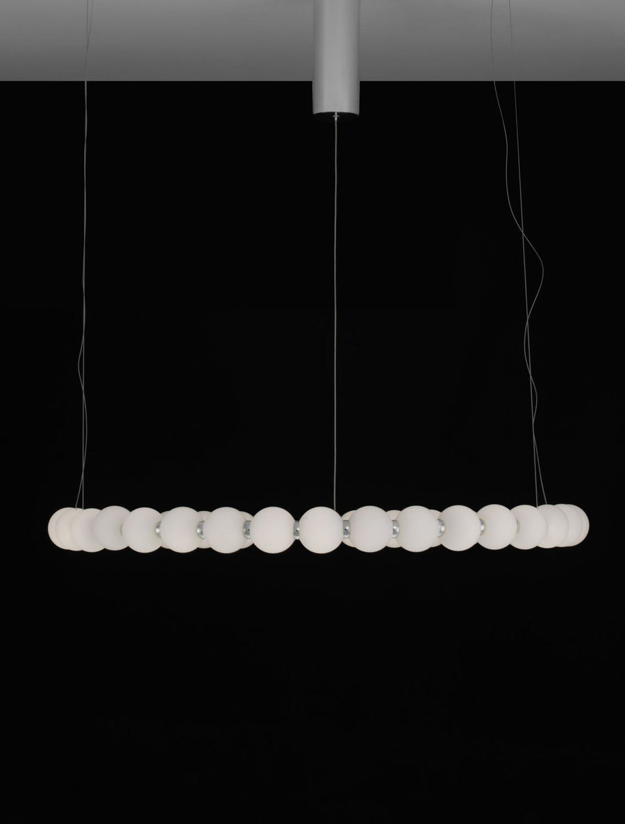 Silhouette allongée de la suspension dans l'obscurité, perles blanches alignées horizontalement