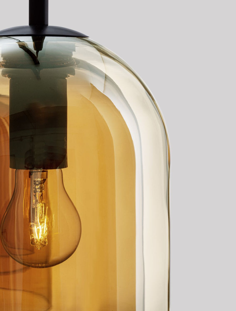 Gros plan sur un abat-jour en verre ambré et l'ampoule à filament allumée