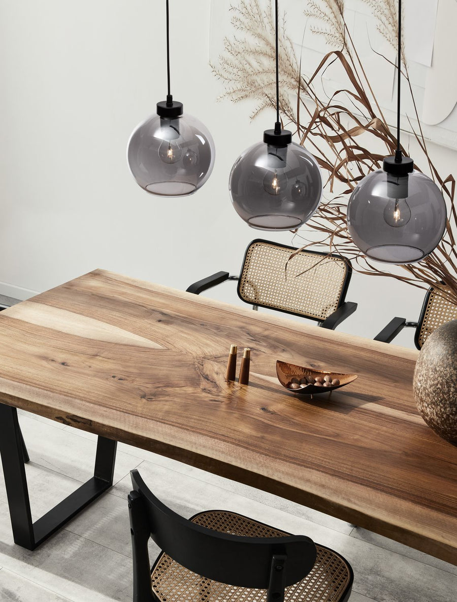 Suspension à trois globes en verre fumé au-dessus d'une table en bois
