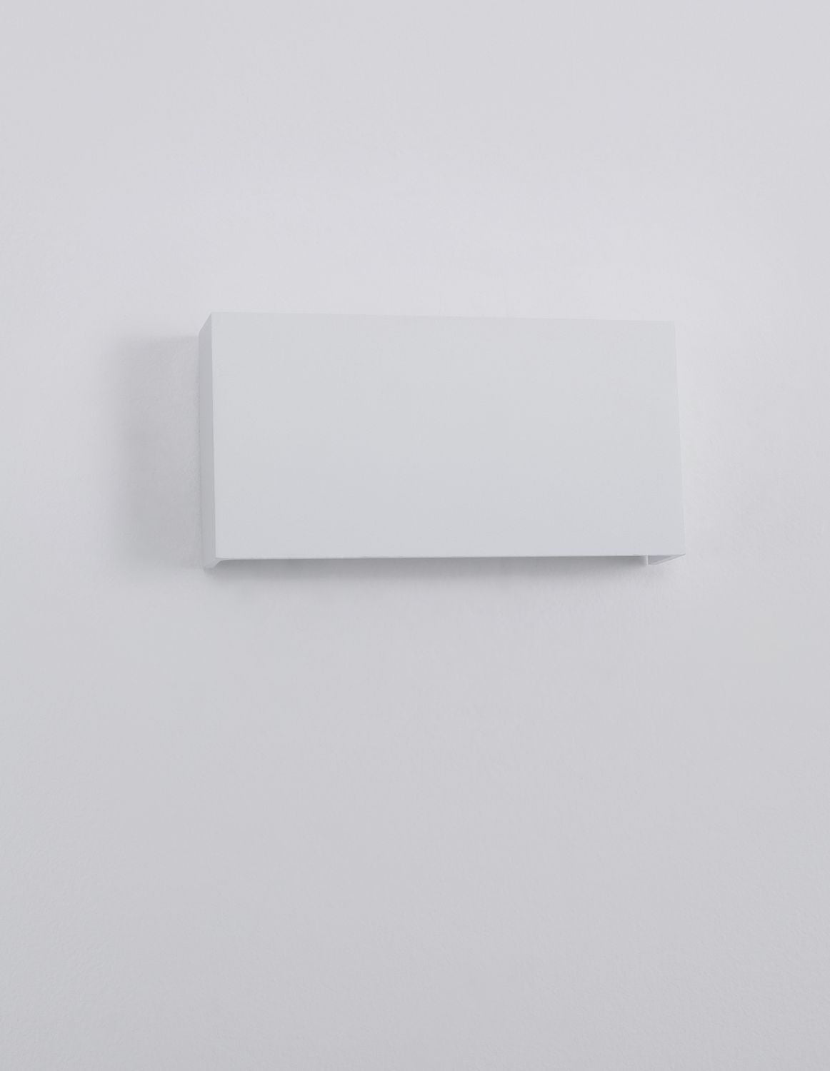 Applique blanche rectangulaire vue de face, fixée sur un mur blanc, non allumée