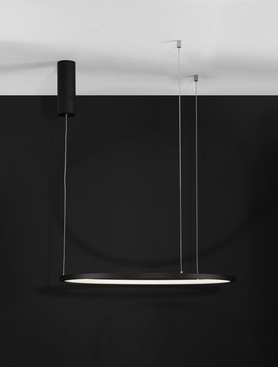 Suspension annulaire noire vue de face sur fond noir, câbles fins et rosace cylindrique