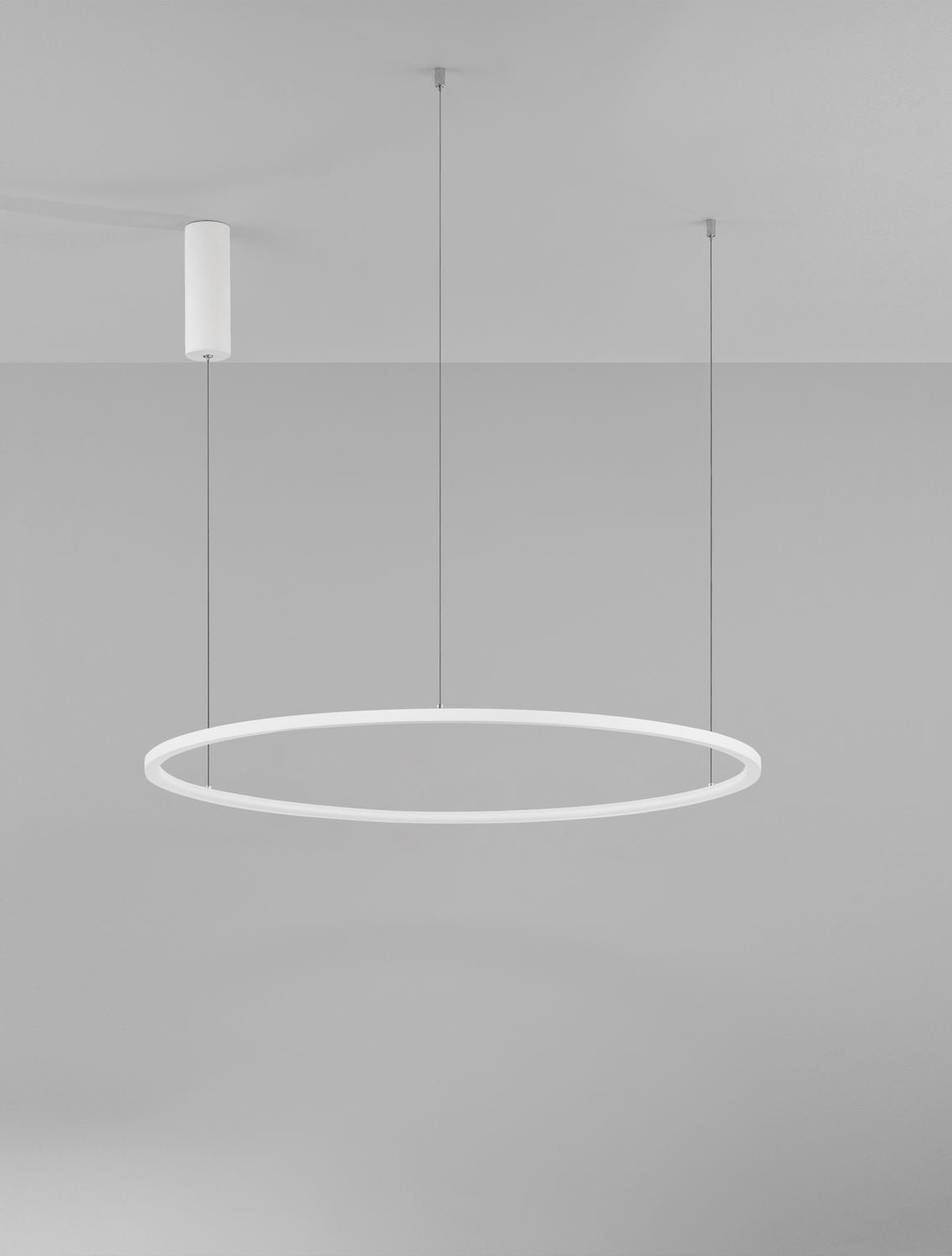 Luminaire éteint dans une pièce claire, trois câbles fins et anneau blanc