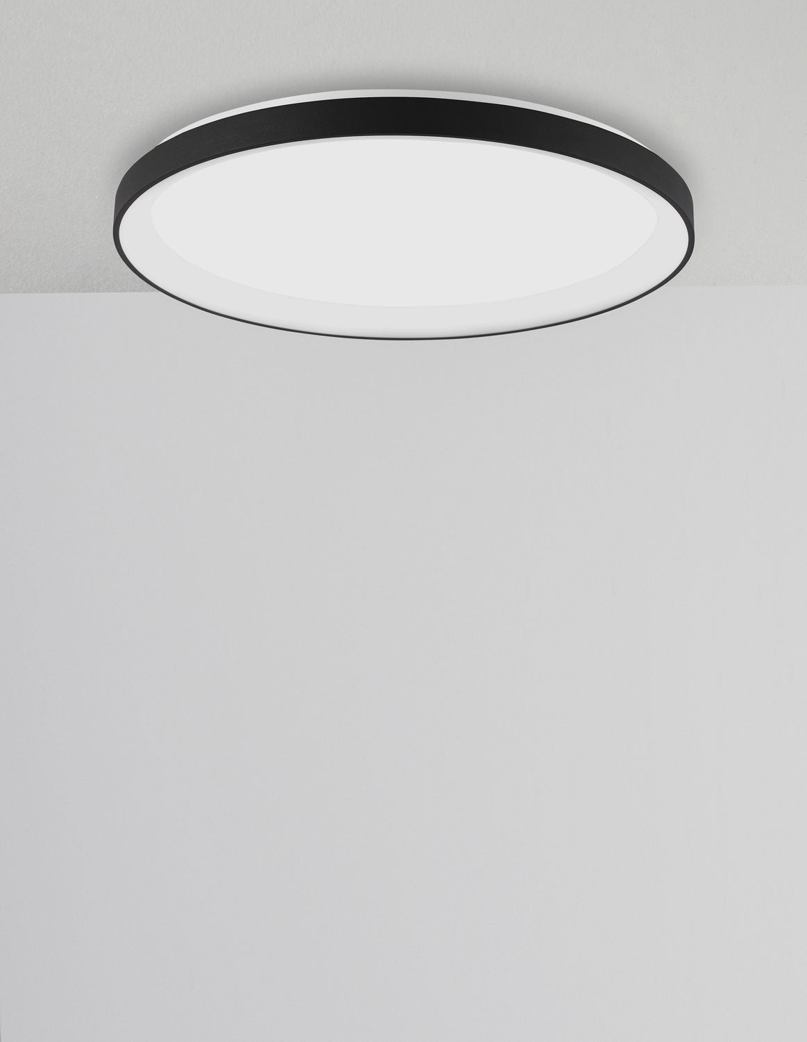 Second angle du luminaire rond au plafond, cerclage noir et verre opalin blanc.