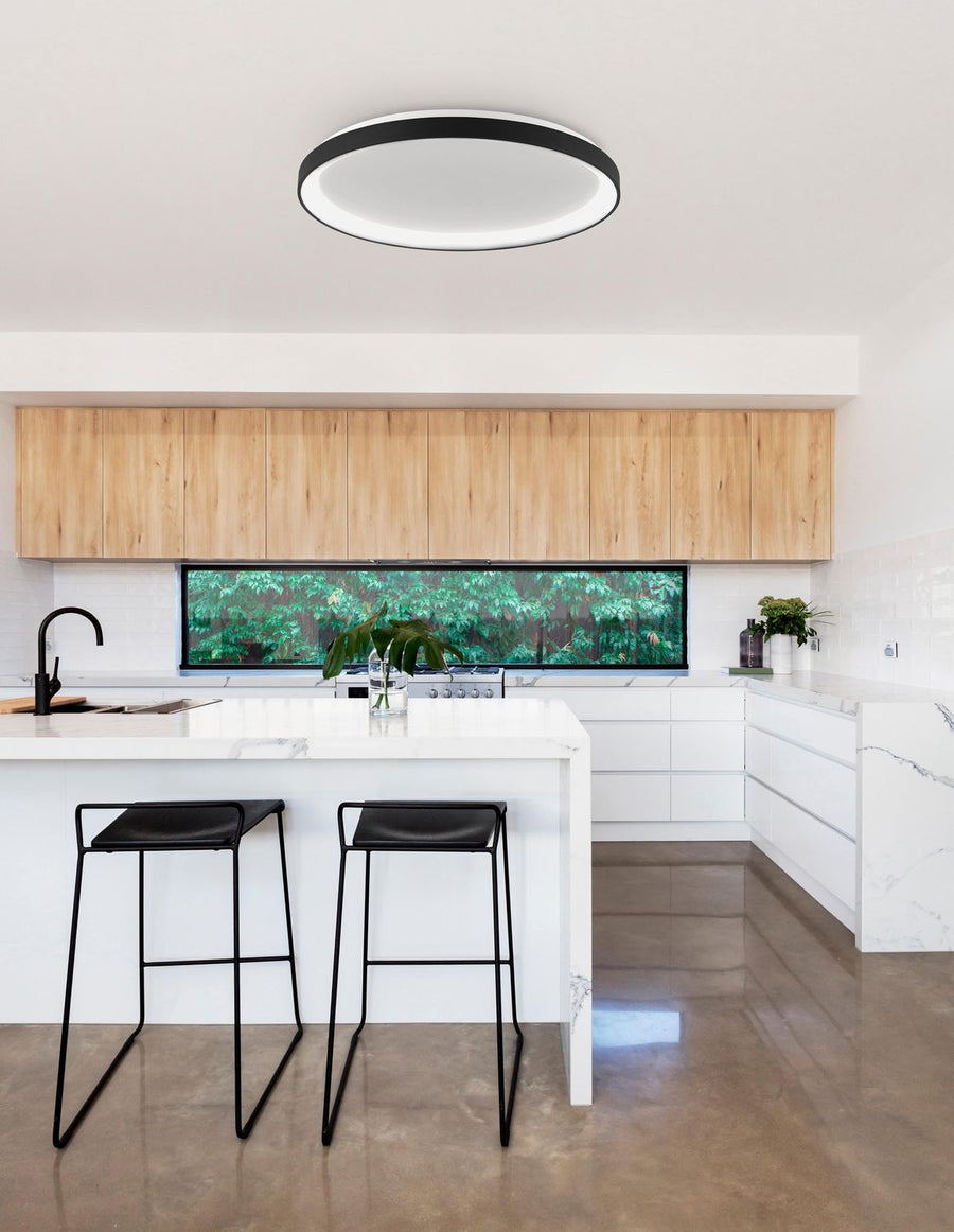Plafonnier rond noir installé au plafond d'une cuisine blanche moderne