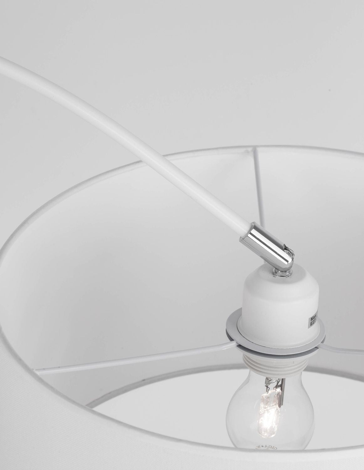 Détail de la douille et de l'ampoule à l'intérieur de l'abat-jour en tissu blanc.