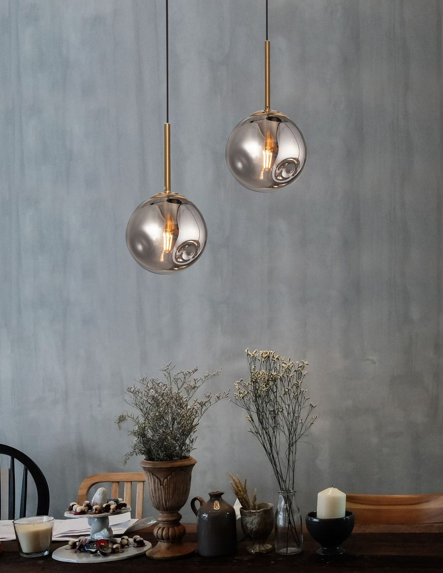 Deux suspensions dorées en verre fumé éclairent une table décorée